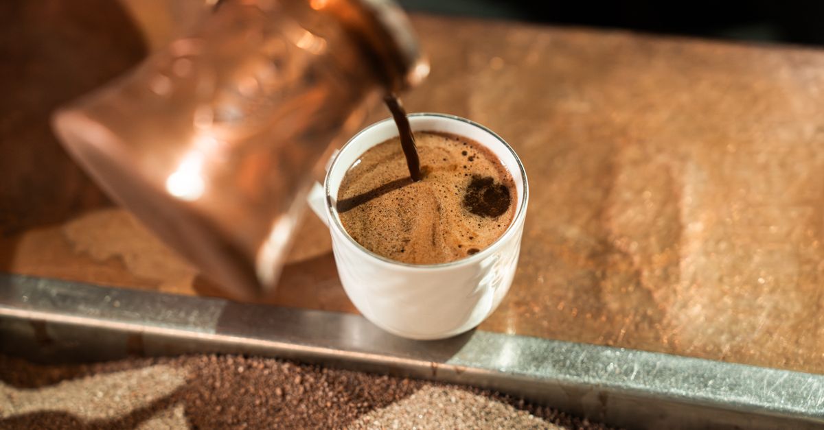 Primer plano de café siendo servido en una taza de cerámica clara