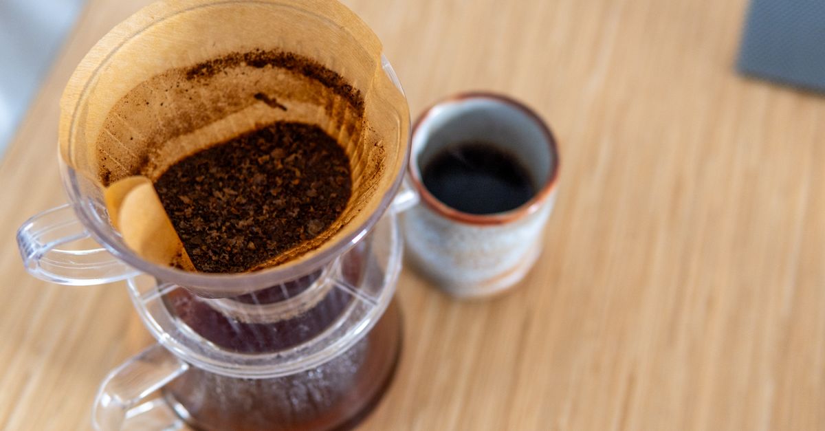 Taza de café filtrado sobre una mesa de madera junto a una libreta de notas